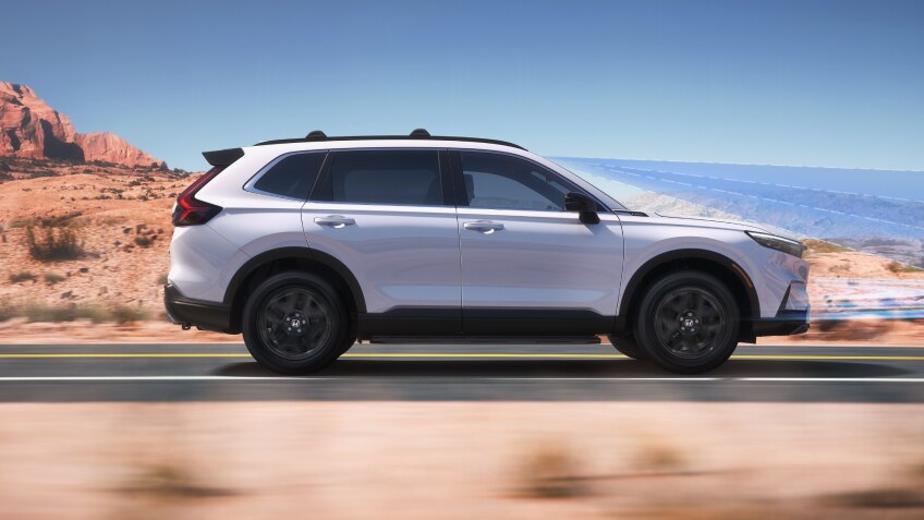 Sideview of white CR-V driving on desert highway. 