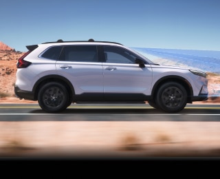 Sideview of white CR-V driving on desert highway.
