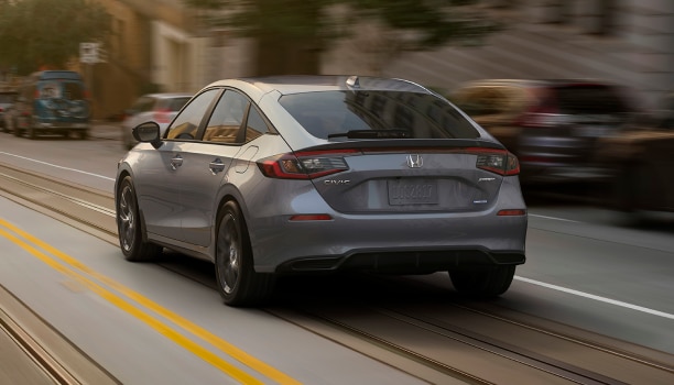 Rear view of grey Hatchback driving on a city street.