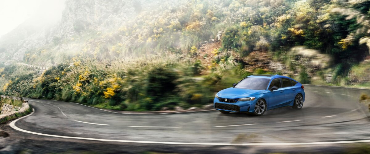 A blue hatchback hugs the corner on a scenic drive.