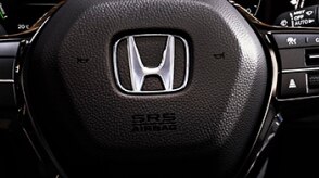Closeup of steering wheel with Honda logo. 