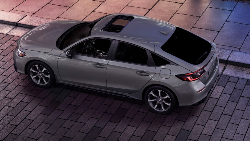 3/4 bird’s eye view of grey Hatchback parked on brick city road.