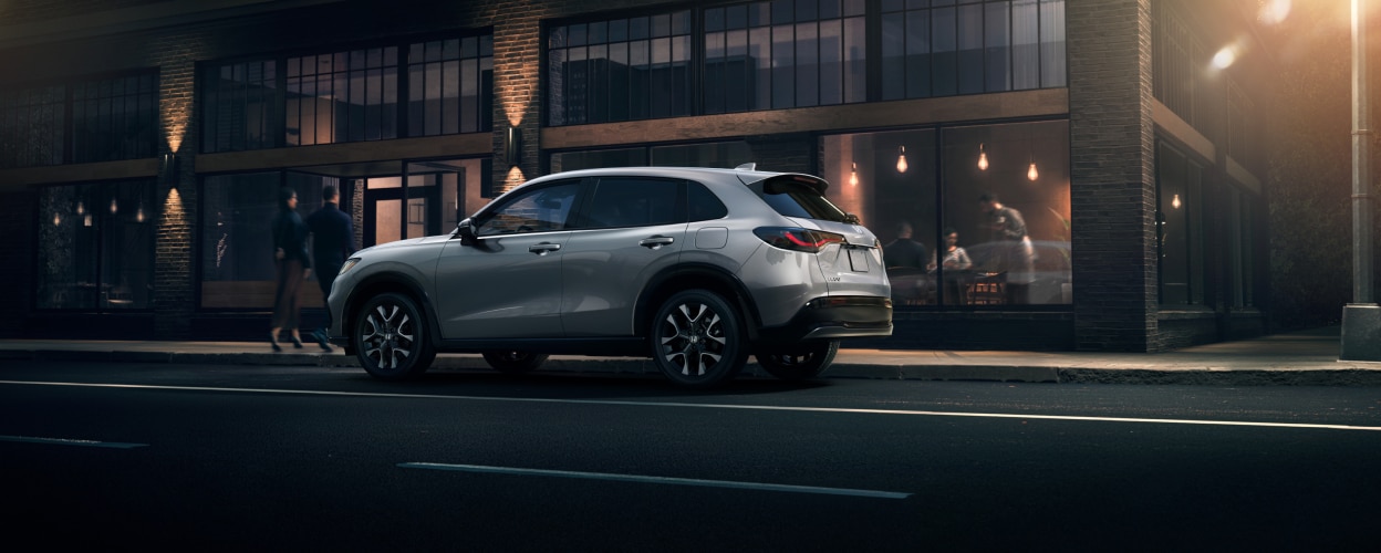 Sideview of grey HR-V parked outside a trendy brickwork restaurant at night. 