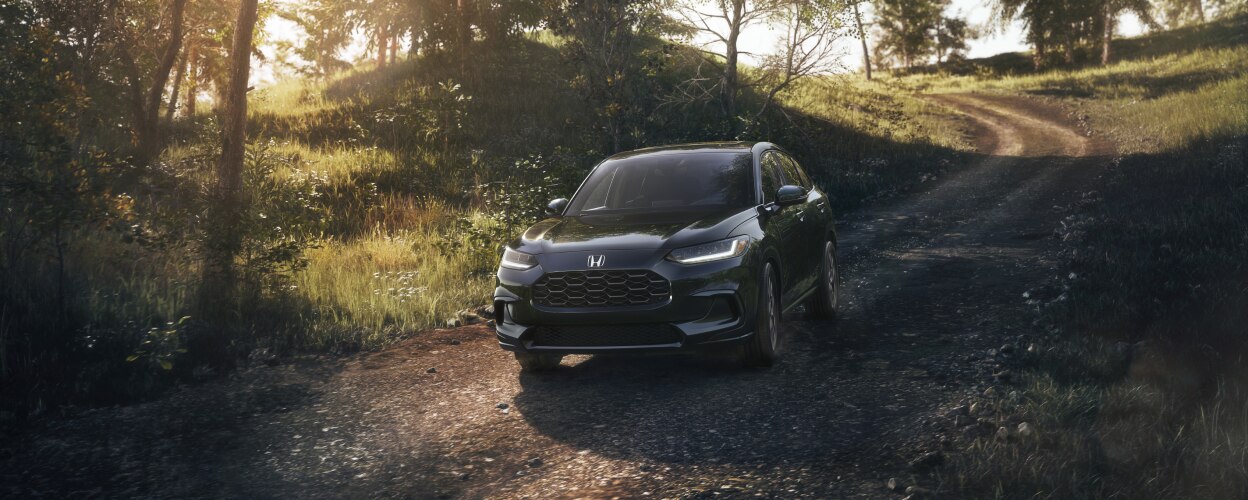 3/4 front view of black HR-V driving toward camera on dirt country road.
