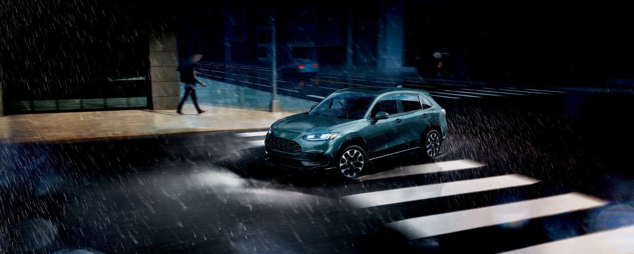 3/4 sideview of Nordic Forest Pearl colour HR-V driving in the rain in the city.