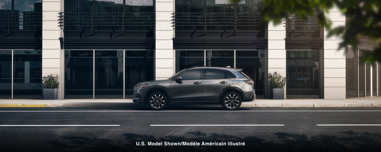 Sideview of grey HR-V parked outside a contemporary building in the city. 