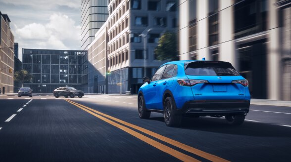 3/4 rear view of a blue HR-V driving in the city.  