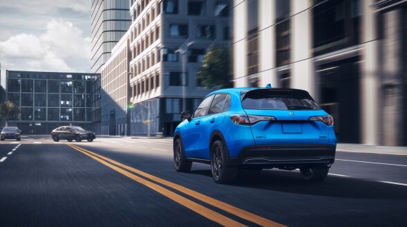 3/4 rear view of a blue HR-V driving in the city.