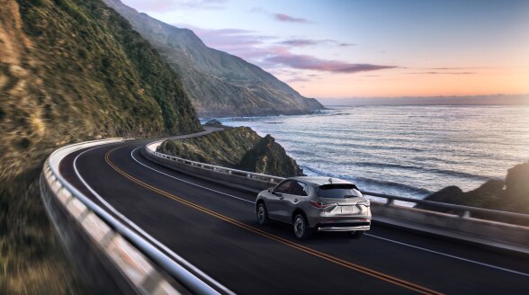 3/4 view of a grey HR-V driving along the coast. 