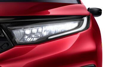 Closeup of headlight on red Odyssey on white space.