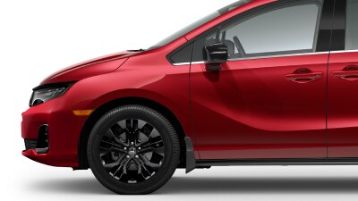 Side view of front end of a red Odyssey on white space, showcasing its black front wheel.