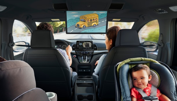 Interior view of Odyssey. Dad driving; Mom in front passenger seat; kid in car seat.