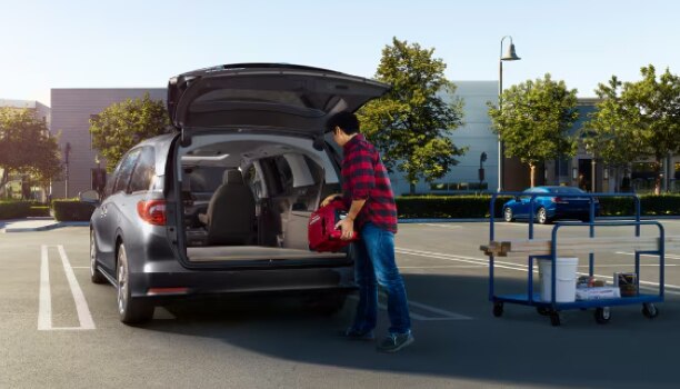 Man loading up Odyssey trunk in empty parking lot.