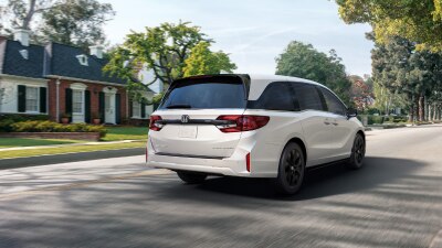 3/4 rear view of white Odyssey braking in suburban street.