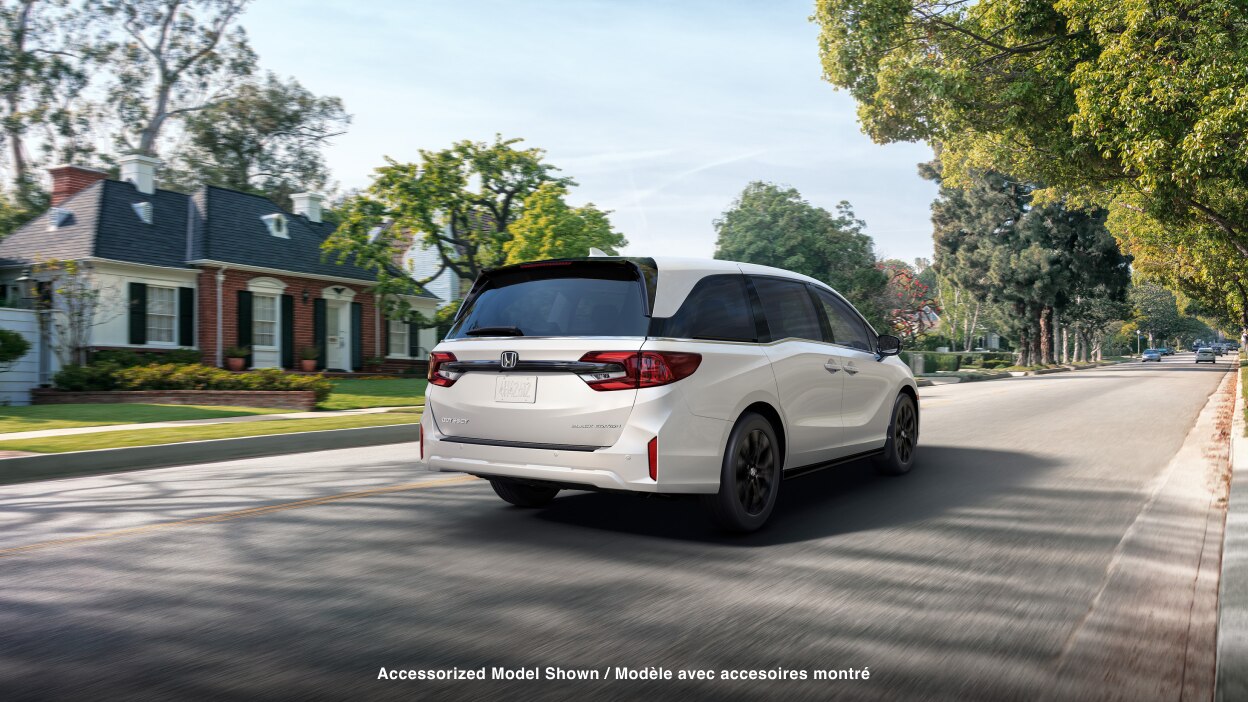 3/4 rear view of white Odyssey braking in suburban street.