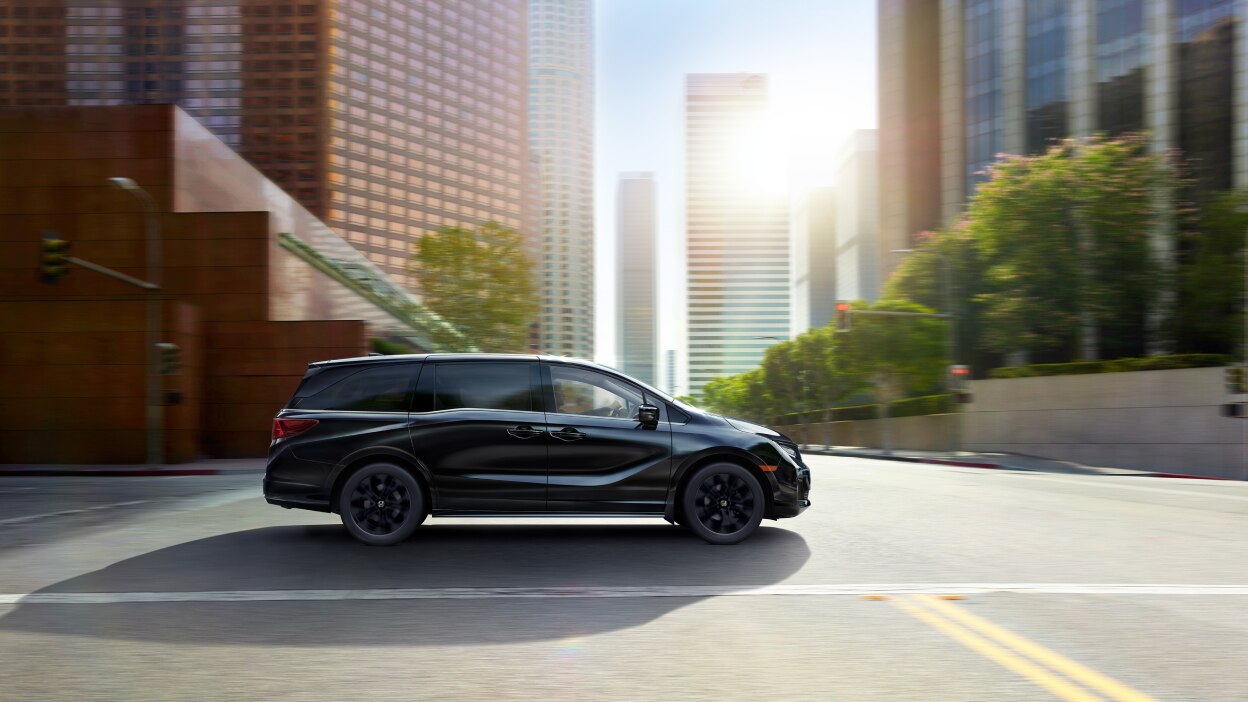 Side front view of black Odyssey driving in city.