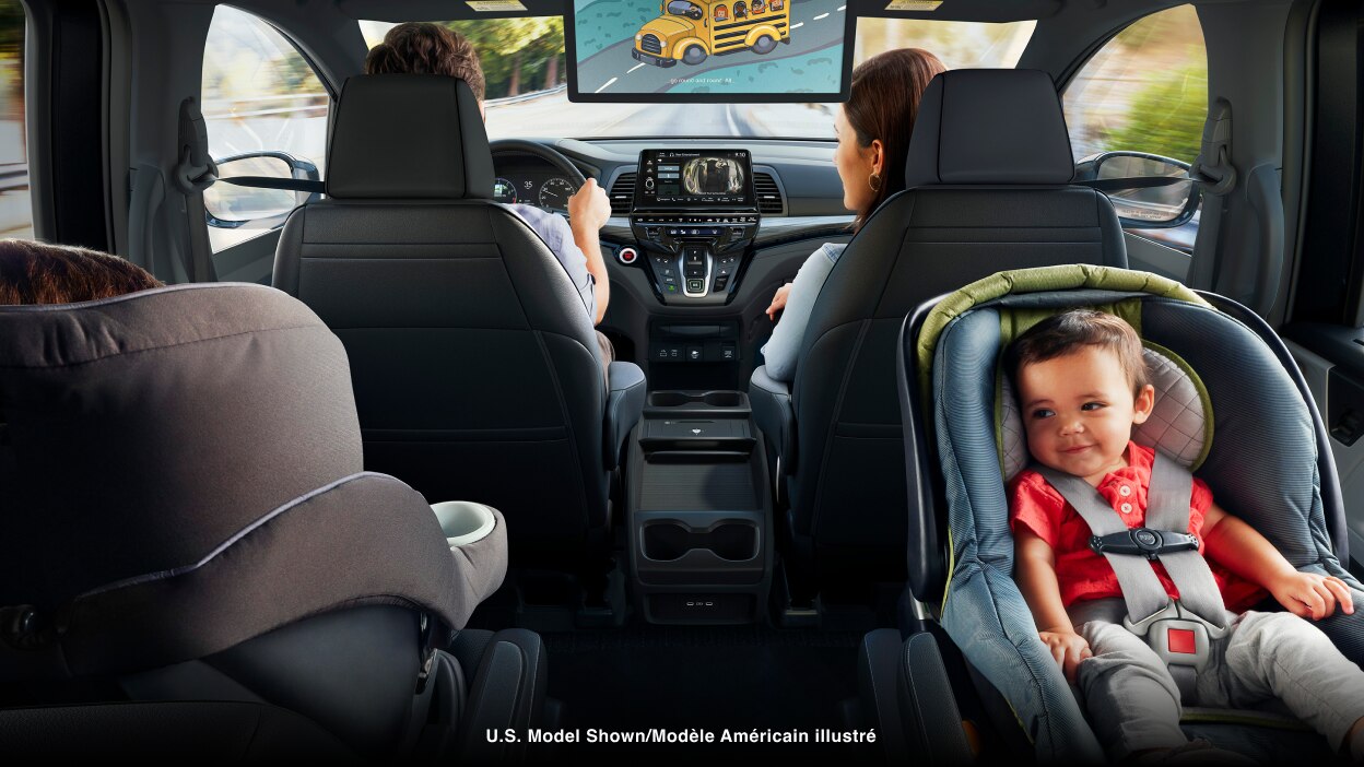 Interior view of Odyssey. Dad driving; Mom in front passenger seat; kid in car seat.