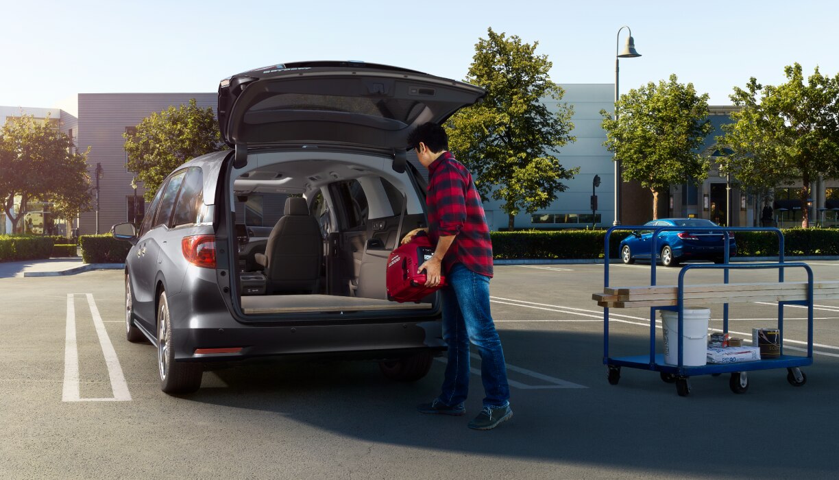 Man loading up Odyssey trunk in empty parking lot.