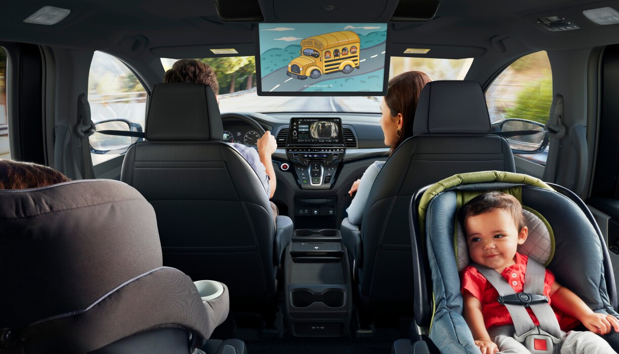 Interior view of Odyssey. Dad driving; Mom in front passenger seat; kid in car seat.