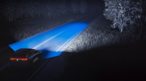 Blue beams are emitted from a vehicle on a dark rural road. 