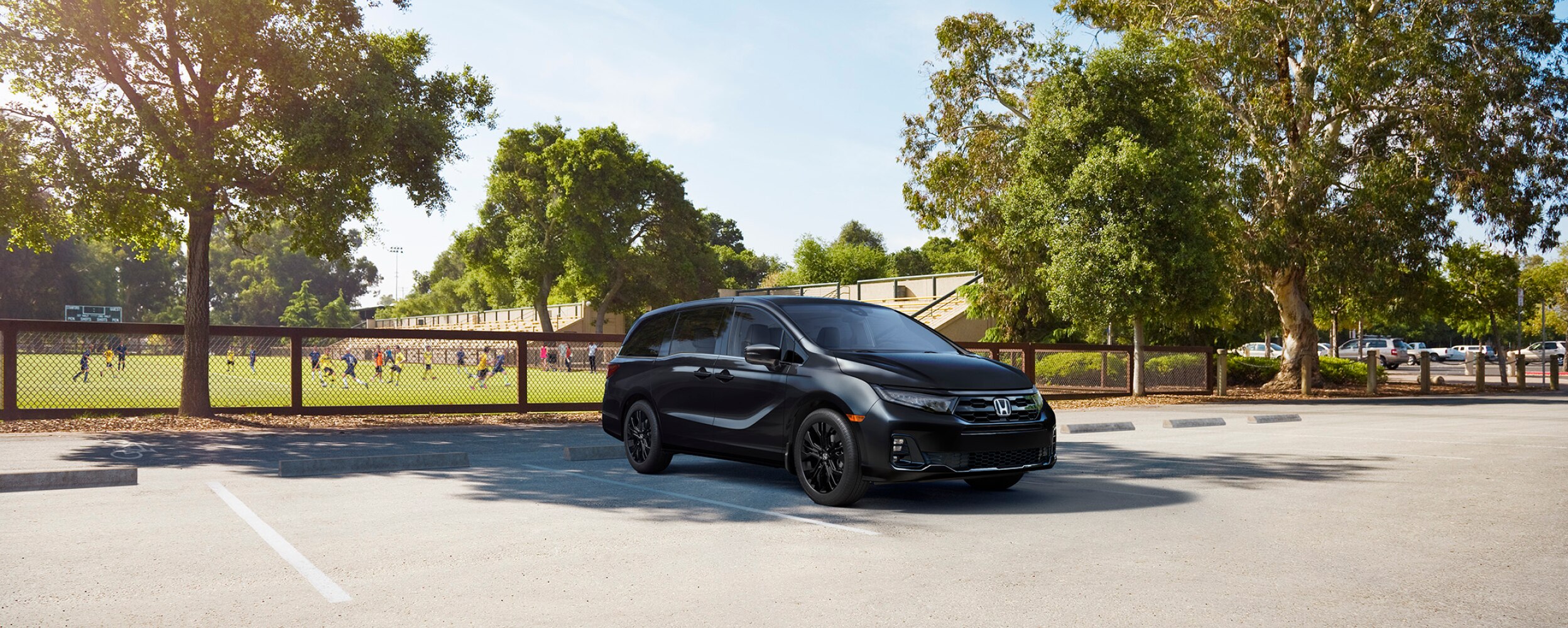 3/4 front view of black Odyssey parked by a soccer field.