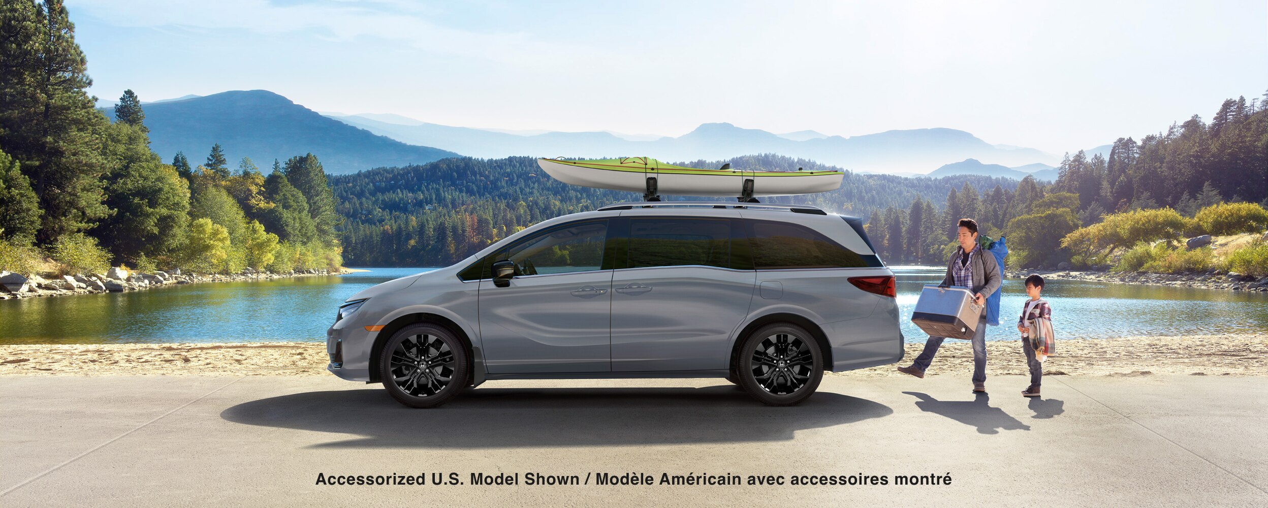 Sideview of white Odyssey, parked lakeside. Dad and kid loading up the trunk.