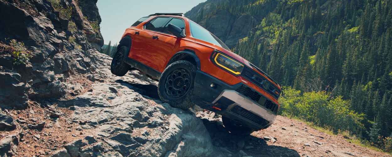 An orange Passport drives over rough mountain terrain. 