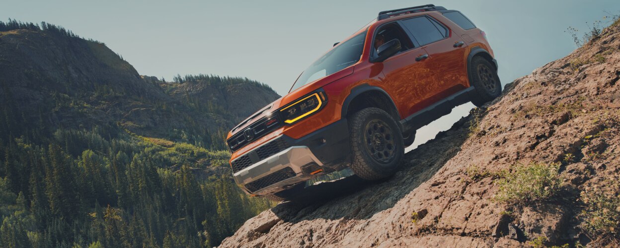 An orange Passport descends down a steep, rocky hill.