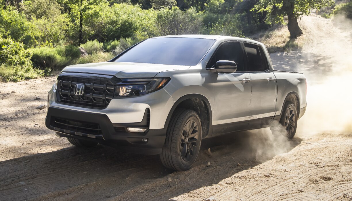 3/4 front view of grey Ridgeline driving on dirt road in wine country.