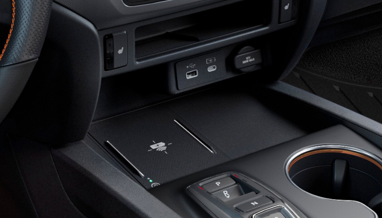 Closeup of USB charging ports and wireless charging pad in centre console.