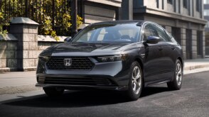 3/4 front view of a grey Accord parked curbside in an upscale urban neighbourhood in the day.